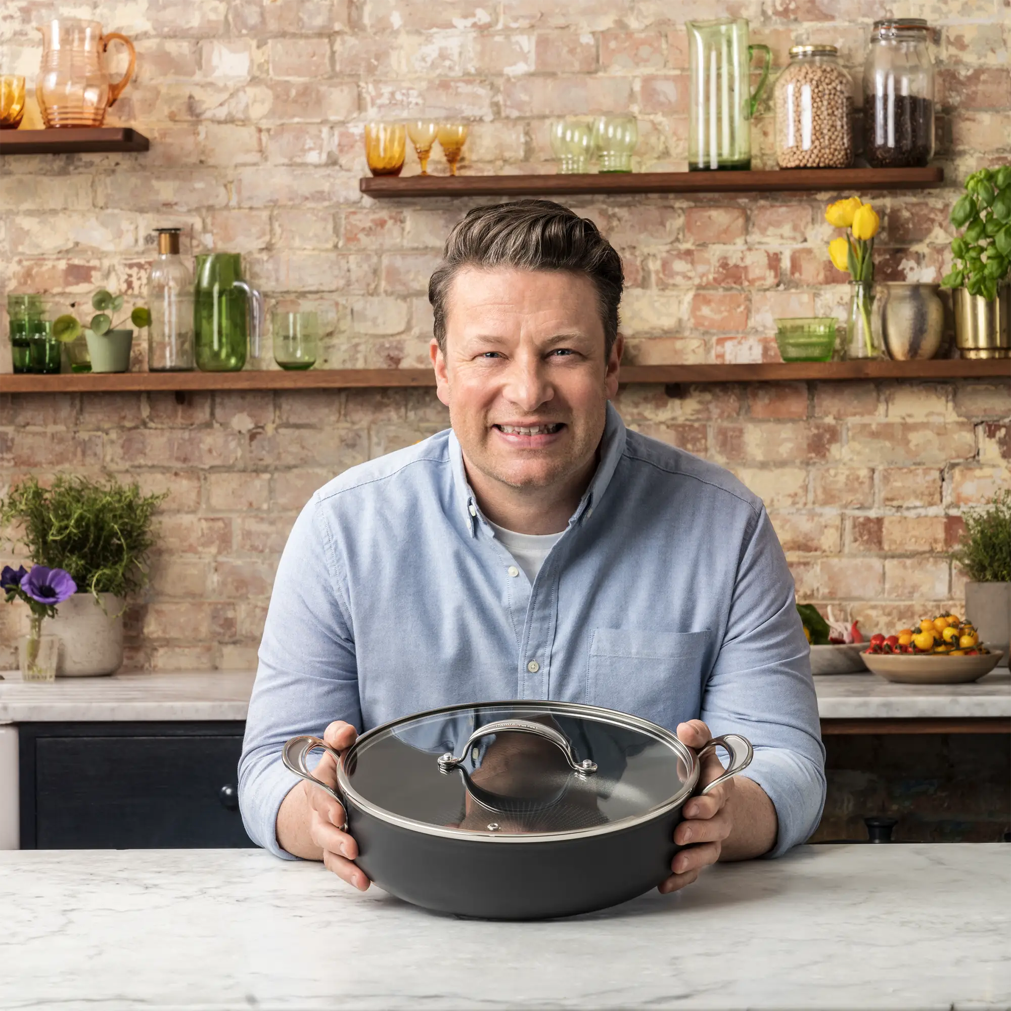 Jamie Oliver holding the Tefal Cooks Classic Induction Non-Stick Hard Anodised All-In-One Pan 30cm